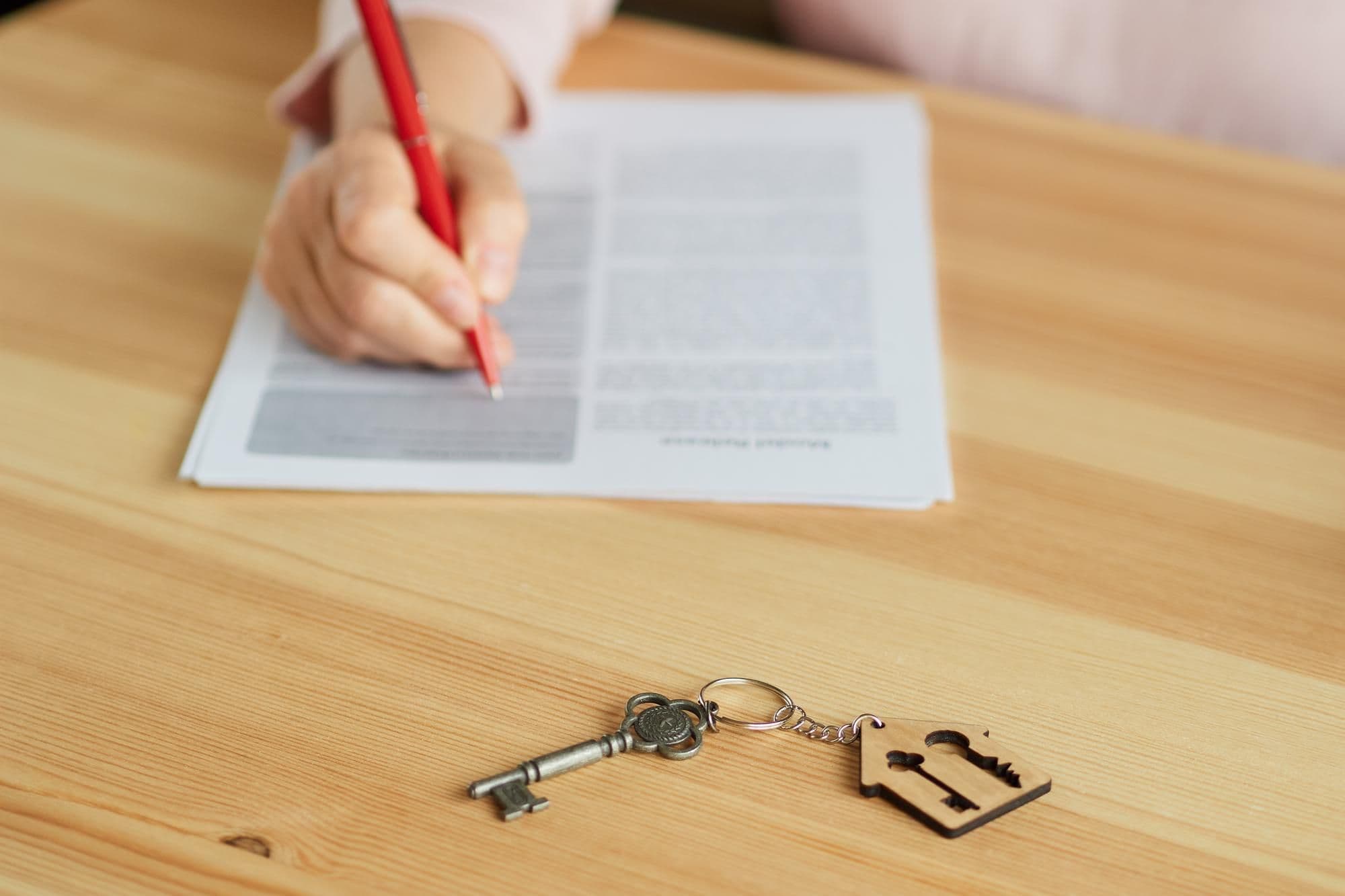 Notar unterzeichnet Immobilienkaufvertrag, im Vordergrund liegen Hausschlüssel auf dem Tisch
